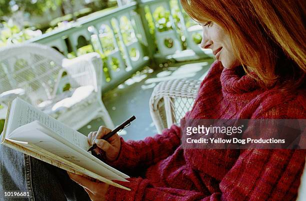 mature woman writing in journal on porch - dog pad stock pictures, royalty-free photos & images
