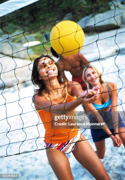 two young women and young man playing volleyball on beach - womens beach volleyball foto e immagini stock