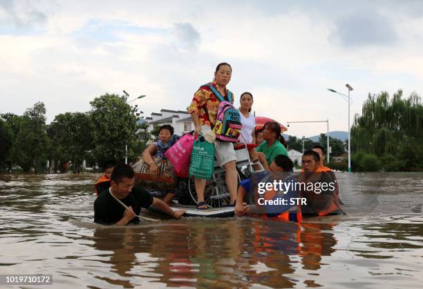 This photo taken on August 19, 2018 shows rescuers evacuating residents through floodwaters after heavy rainfall caused by Typhoon Rumbia in Huaibei...