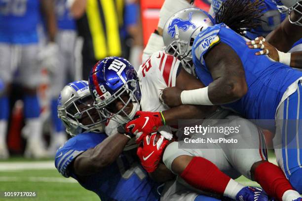 New York Giants running back Jonathan Stewart is tackled by Detroit Lions defensive tackle Ricky Jean Francois and Detroit Lions linebacker Jarrad...