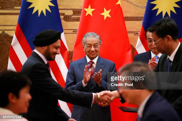 Malaysian Prime Minister Mahathir Mohamad and his Chinese counterpart Li Keqiang claps as delegates exchange documents during a signing ceremony at...