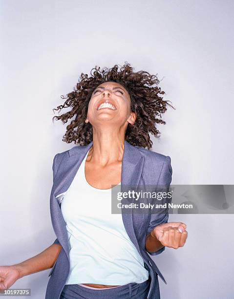 young woman jumping and smiling - clenching teeth stock-fotos und bilder