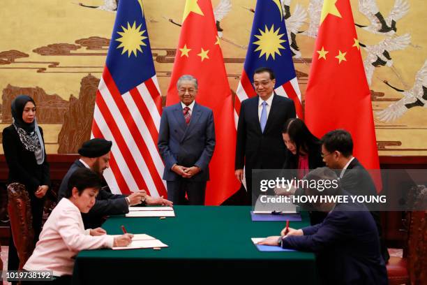 Malaysia's Prime Minister Mahathir Mohamad and China's Premier Li Keqiang look on as delegates take part in a signing ceremony at the Great Hall of...