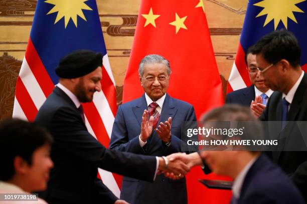 Malaysia's Prime Minister Mahathir Mohamad and China's Premier Li Keqiang clap as delegates exchange documents during a signing ceremony at the Great...