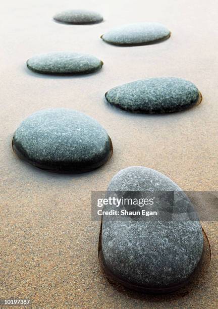 stepping stones across sand and shallow water, close-up - stepping stone stock-fotos und bilder