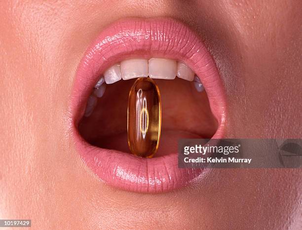 young woman with capsule between teeth, close-up - chewing with mouth open stock pictures, royalty-free photos & images