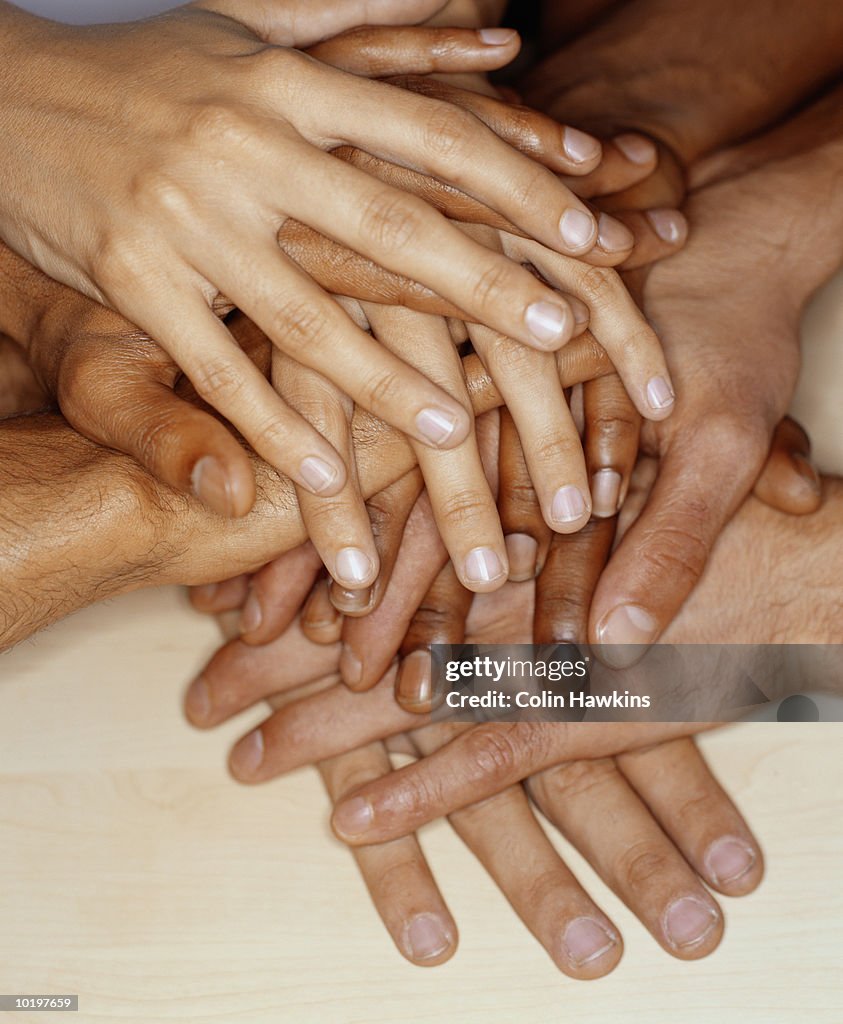 Group of people stacking hands on top of each other, close-up