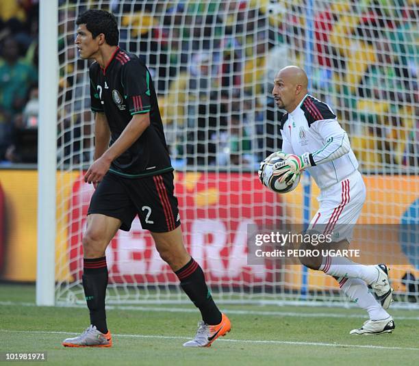 Mexico's goalkeeper Oscar Perez runs with the ball as Mexico's defender Francisco Rodriguez looks at the field during their Group A first round 2010...