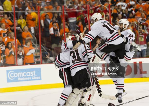 Patrick Sharp of the Chicago Blackhawks jumps for joy with teammates Andrew Ladd and Antti Niemi to celebrate after Patrick Kane scored the winning...