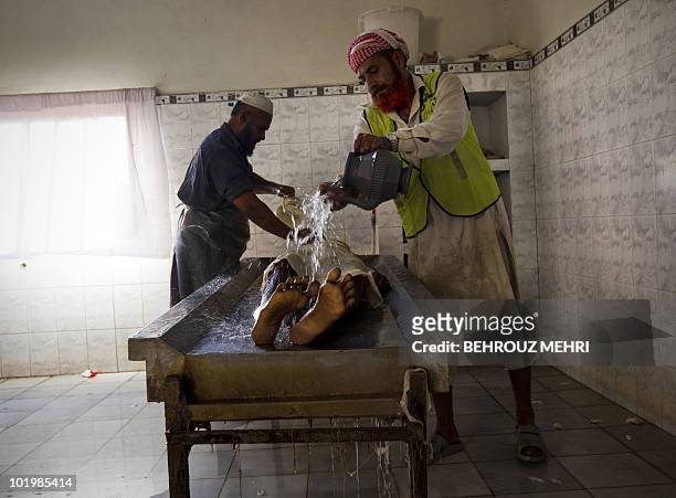 Pakistani employees wash a body of an elderly man to prepare him for a burial ceremony at The Edhi Morgue in Karachi on February 20, 2010. The Edhi...