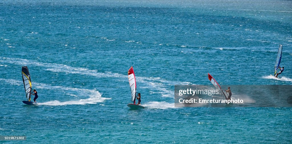 Three surfers making a jibe..