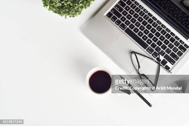 top view desk at work place with laptop, coffee mug, spectacles and green plant copy space flat lay - flatlay stock-fotos und bilder
