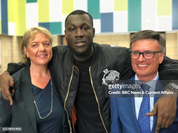 Stormzy poses with poses with CEO of Harris Federation, Sir Dan Moynihan and a former teacher as he visits his old school Harris City Academy in...