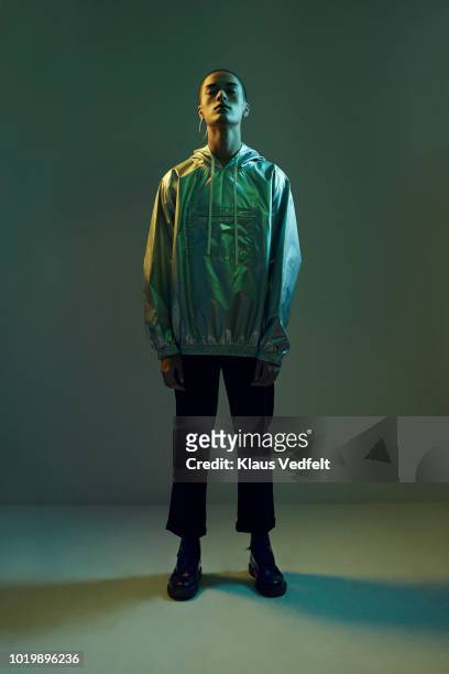 young man standing in coloured lights with closed eyes , shot on studio - gray pants photos et images de collection