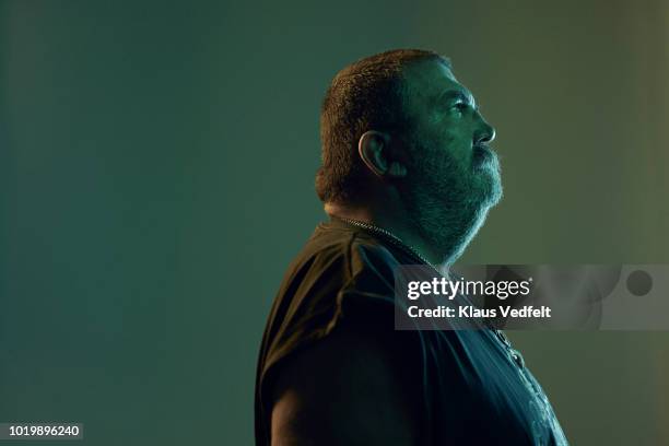 mature rough looking man photographed on studio with coloured lighting - white t shirt studio imagens e fotografias de stock
