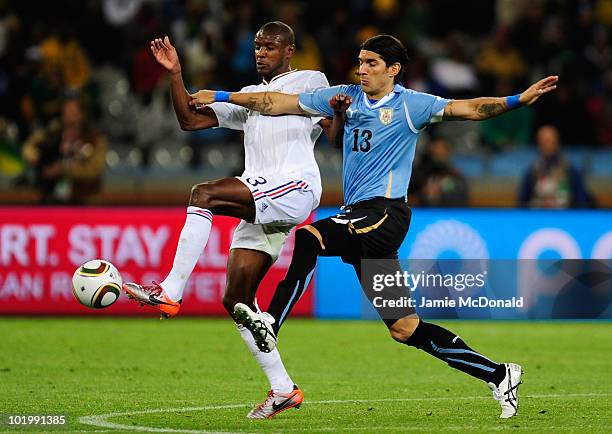 Eric Abidal of France and Sebastian Abreu of Uruguay battle for the ball during the 2010 FIFA World Cup South Africa Group A match between Uruguay...