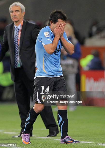 Raymond Domenech head coach of France looks on as Nicolas Lodeiro of Uruguay holds his head in his hands as he is sent off during the 2010 FIFA World...