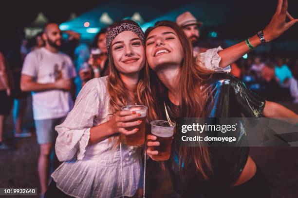 two young women enjoying a night at the music festival - youth culture music stock pictures, royalty-free photos & images