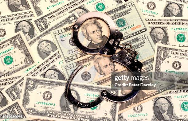handcuffs sitting on top of us paper currency - culpabilidad fotografías e imágenes de stock