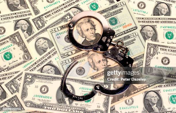 handcuffs sitting on top of us paper currency - korruption bildbanksfoton och bilder