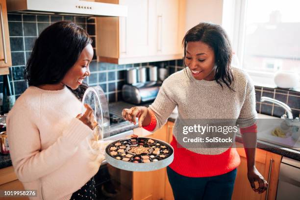 sharing christmas chocolates with her sister - sharing chocolate stock pictures, royalty-free photos & images