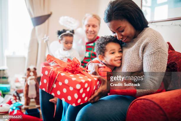 geschenk geben mit seiner mutter in der weihnachtszeit - child giving gift stock-fotos und bilder