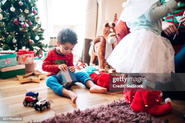 little boy opening a gift at christmas time - real christmas tree stock pictures, royalty-free photos & images