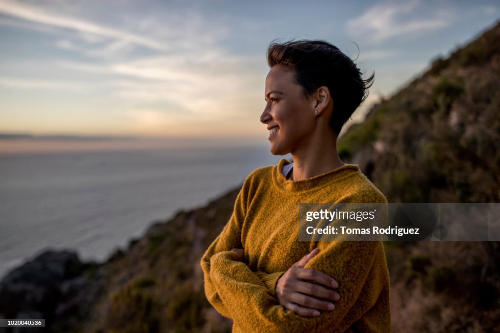 Smiling woman taking a break on a hiking trip looking at view at sunset