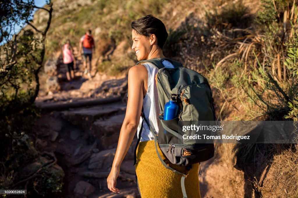 Rear view of smiling woman with friends hiking on a mountain trail