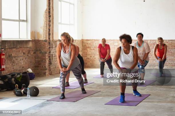 female fitness trainer leading a class at the gym - real body fotografías e imágenes de stock