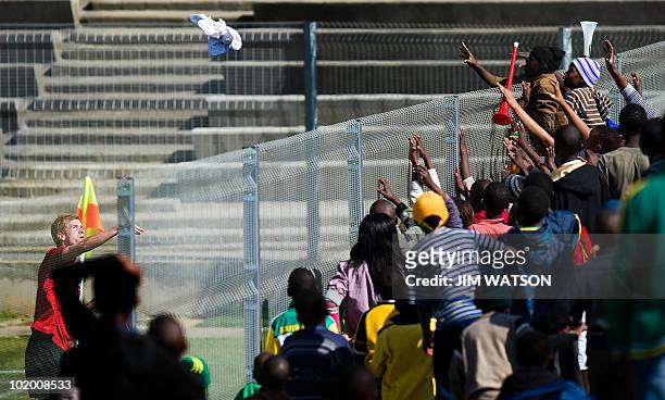New Zealand's midfielder Aaron Clapham throws a jersey over the fence to fans during an open public training session at Sinada Stadium in Benoni on...