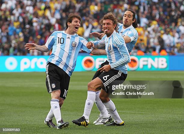 Gabriel Heinze of Argentina celebrates with teammates Lionel Messi and Martin Demichelis after he scores the opening goal during the 2010 FIFA World...