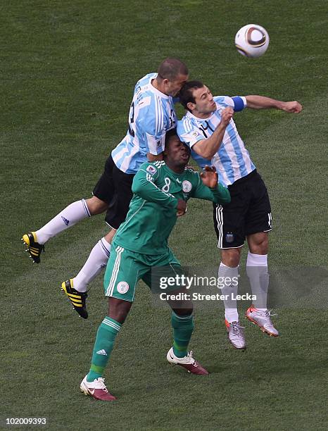 Walter Samuel and Javier Mascherano of Argentina battle for the ball with Yakubu Ayegbeni of Nigeria during the 2010 FIFA World Cup South Africa...