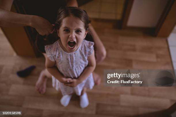 displeased child and her mother making hairstyles - angry mom stock pictures, royalty-free photos & images