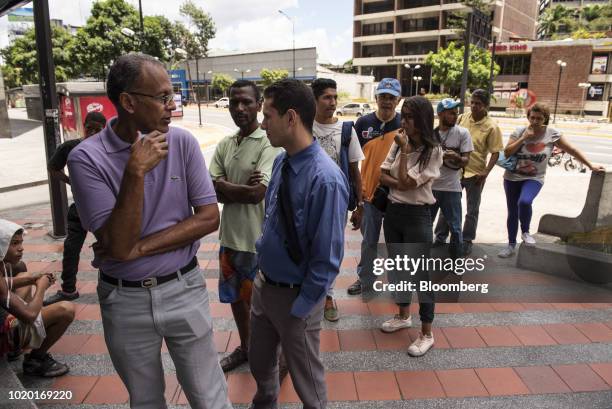 People wait in line to withdraw new sovereign bolivar banknotes at automated teller machines in Caracas, Venezuela, on Monday, Aug. 20, 2018. The...