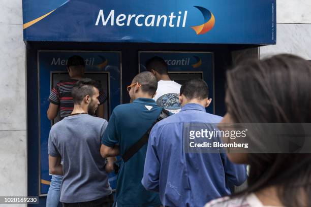 People wait in line to receive new sovereign bolivar banknotes at Mercantil Bank automated teller machines in Caracas, Venezuela, on Monday, Aug. 20,...