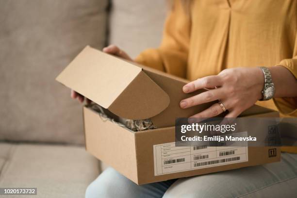 young woman opening a package - caixa aberta imagens e fotografias de stock