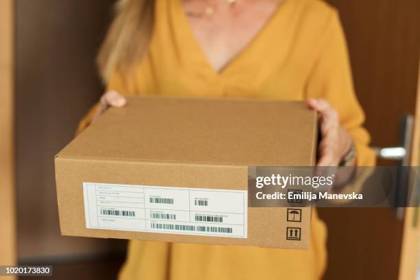 young woman receiving a package - recibir fotografías e imágenes de stock