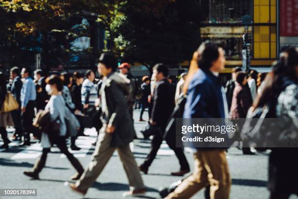 busy commuters crossing street during office rush hour in downtown district in tokyo - anzug ausland stock-fotos und bilder