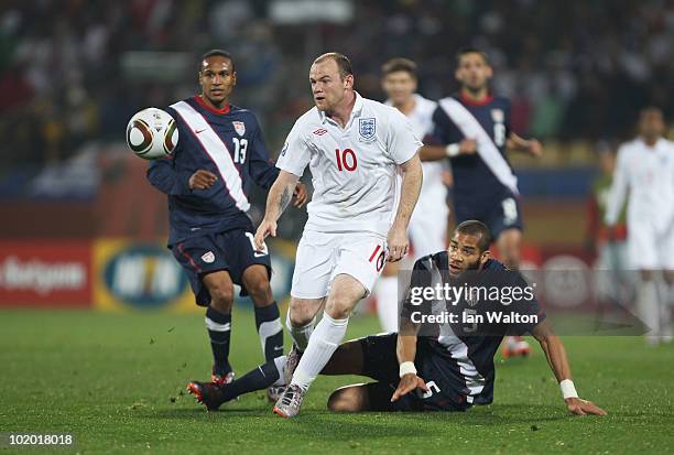 Wayne Rooney of England rides the tackle by Oguchi Onyewu of the United States during the 2010 FIFA World Cup South Africa Group C match between...