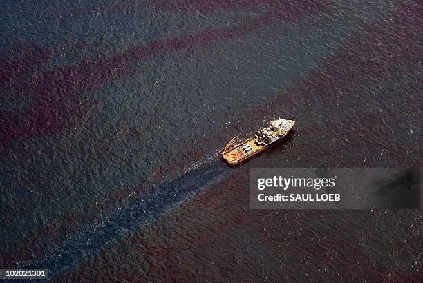 Support ship related to the collection of oil from over the site of the BP Deepwater Horizon oil well transitions through a sheen of oil as workers...