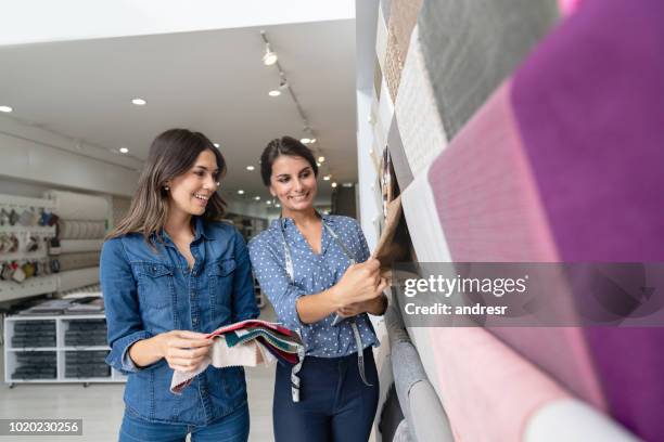 mujer elegir a telas en una tienda textil y hablando con una comercial - fábrica textil fotografías e imágenes de stock