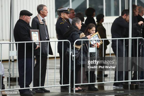 Famiy and relatives hold pictures as the remains of New Zealand Defence Force personnel repatriated from Malaysia and Singapore arrive at Auckland...