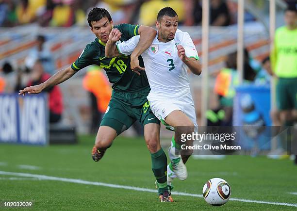 Nadir Belhadj of Algeria is tackled by Aleksandar Radosavljevic of Slovenia during the 2010 FIFA World Cup South Africa Group C match between Algeria...