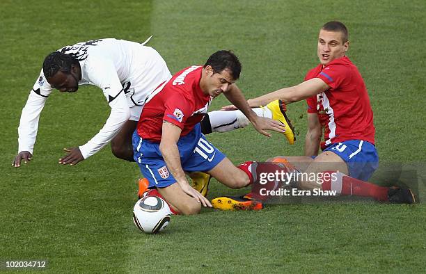 Prince Tagoe of Ghana is tackled by Dejan Stankovic and Nemanja Vidic of Serbia during the 2010 FIFA World Cup South Africa Group D match between...