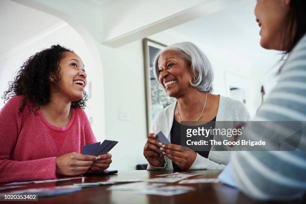 smiling grandmother playing cards with family at home - carta de baralho jogo de lazer - fotografias e filmes do acervo