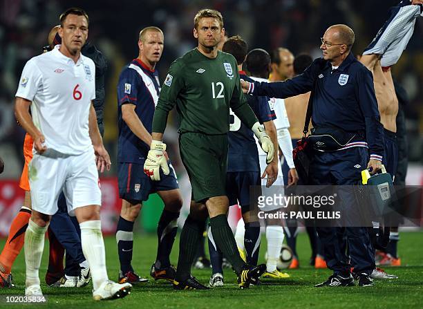England's defender John Terry and a member of medical staff comfort goalkeeper Robert Green at the end of their 2010 World Cup group C first round...