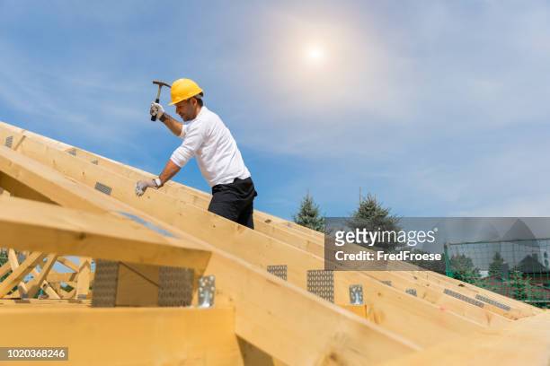 construction industry - roofer carpenter working on roof - roofer stock pictures, royalty-free photos & images