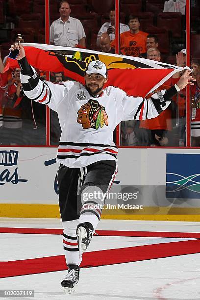 Dustin Byfuglien of the Chicago Blackhawks skates with the Blackhawks flag after teammate Patrick Kane scored the game-winning goal in overtime to...