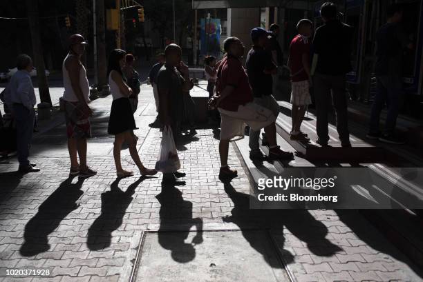 People wait in line to withdraw new sovereign bolivar banknotes at anautomated teller machines in Caracas, Venezuela, on Monday, Aug. 20, 2018. The...